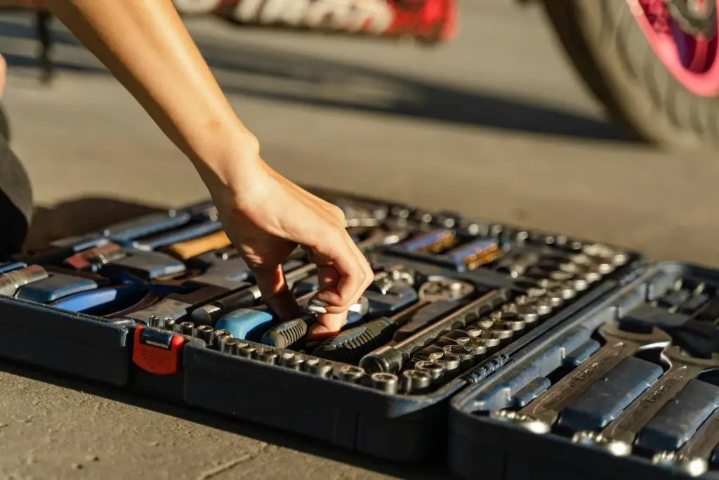 Close-up of a man's hands neatly organizing DIY car maintenance tools.