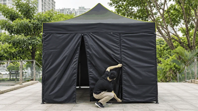 Man attaching pop up canopy with sidewalls.