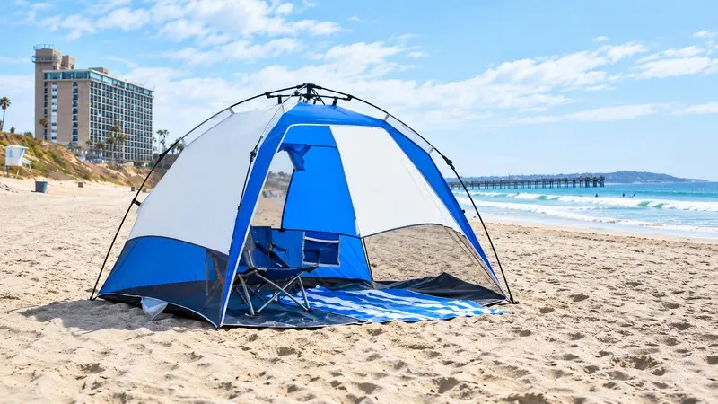 Tenda da campeggio impermeabile blu e bianca sulla spiaggia.
