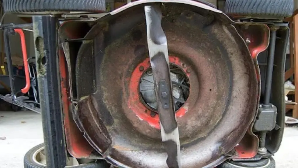 Lawn mower tipped over showing the blade