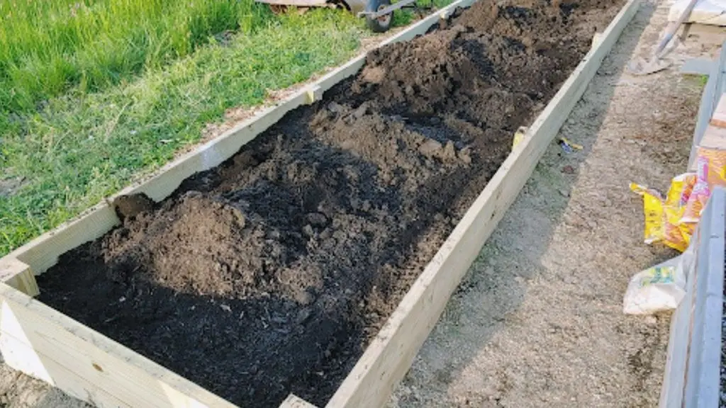 long wooden raised planter box filled with dark soil