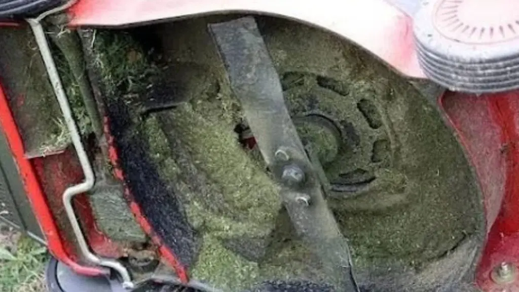Close-up of a lawn mower blade covered in grass for a bench grinder for sharpening lawn mower blades