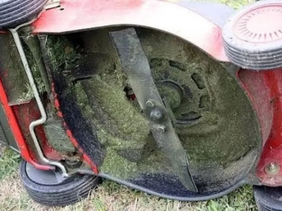 Close-up of a lawn mower blade covered in grass for a bench grinder for sharpening lawn mower blades