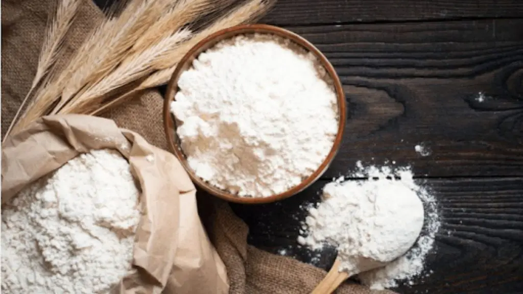 Fresh flour milled with a small flour mill for home use in a bowl with wheat