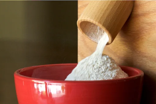 Molino de harina pequeño para uso doméstico que vierte harina fresca en un recipiente.