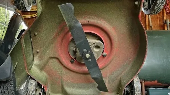 : Worn mower blade with grass buildup, a sign it needs a proper sharpening angle